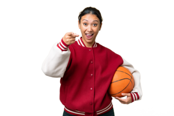 Young Uruguayan woman playing basketball over isolated wall  over isolated chroma key background surprised and pointing front
