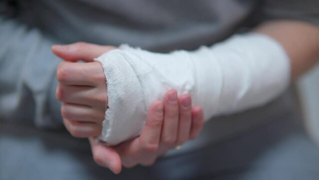 Man with plaster cast on arm. The difficulty of self-movement of the hand at a fracture. Painful heavy movements of broken finger hands close-up.