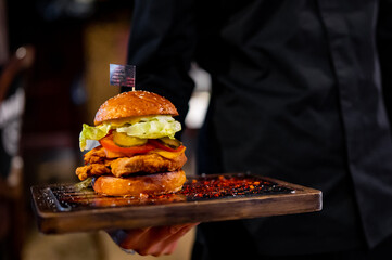 Men's waiter hands hold a tray with a cheeseburger in pub