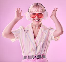 Fashion, beauty and happy woman isolated on pink background excited, wow and dancing on creative aesthetic. Earmuffs, clothes and cool, retro and punk sunglasses of gen z model or person in studio
