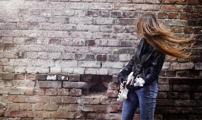 Beautiful young girl rocker with electric guitar. A rock musician girl in a leather jacket with a...