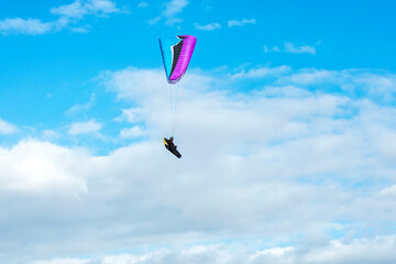 Paraglider paragliding on the background of blue cloudy sky