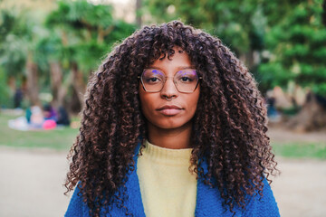 Close up portrait of young serious african american woman with goggles and curly hair looking...