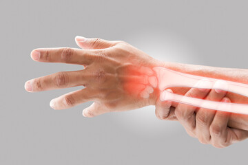 A man massaging painful wrist on a gray background. Pain concept. Osteoporosis