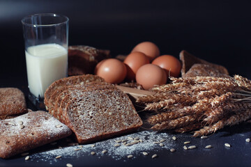 Fresh loaves of bread with wheat and gluten on a black table. Bakery and grocery concept. Fresh,...