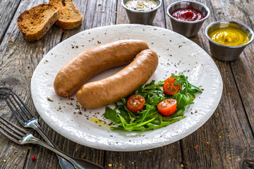 Breakfast - boiled sausages, bread and fresh vegetables served on wooden table
