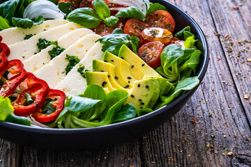 Fresh vegetable salad with robiola cheese and avocado on wooden table
