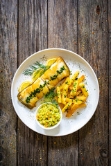 Fish dish - fried cod with French fries and cabbage salad on wooden table
