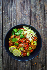 Asian food - chicken nuggets, noodles, stir fried vegetables, soy sauce, cabbage and shimeji mushrooms on wooden table
