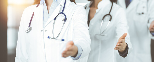 Group of doctors are standing as a team while offering their helping hands for shaking hand or saving people's life. Medicine concept during Coronavirus pandemic. Covid-2019