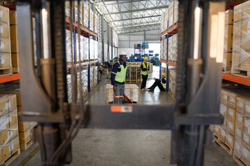Worker in auto parts warehouse use a handcart to work to bring the box of auto parts into the storage shelf of the warehouse waiting for delivery to the car assembly line