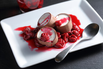 Slices of chocolate coated ice cream served with cherry jam on a rectangular white dish