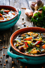 Delicious soup - cooked chicken breast, boiled fresh vegetables, lentils, peas and chickpeas on wooden table
