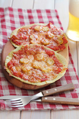 Sausage and tomatoes tortilla pizzas on a wooden board served with light beer - 575292654
