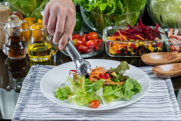 woman chef mix fresh baby cos salad and pour salad dressing in glass blow. Organic Vegetables mix all green salad In glass bowl. Breakfast fresh salad and clean vegetable.