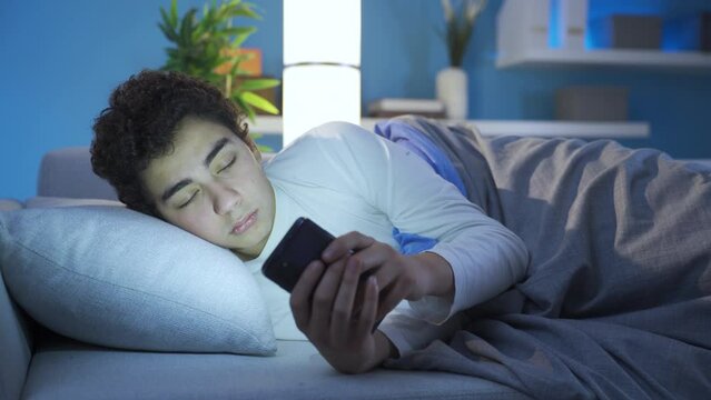 Phone addicted teenager.
Phone addicted adolescent male lying on sofa at home.
