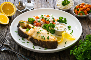 Fish dish - fried halibut with white rice, peas and carrots on wooden table
 - obrazy, fototapety, plakaty