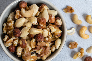 Mixed nuts in ceramic bowl on table, close-up view