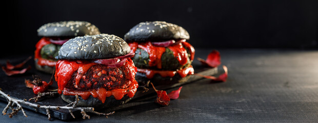 Halloween food, black burgers on dark background with copy space