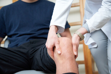 Traumatologist examining an athlete's knee after an injury.  Knee stability assessment on anterior cruciate ligament injury. Crop view.