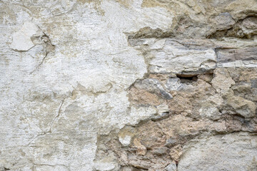 Background of old wall with collapsed plaster. Texture of shabby weathered building surface. Destroyed brick wall with fallen plaster. Copy space. Selective focus.