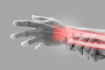A man massaging painful wrist on a gray background. Pain concept. Osteoporosis - obrazy, fototapety, plakaty