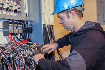 Young Male electrician protected by helmet is hard at work connecting cables