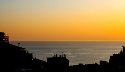 Fototapeta premium View on sea through buildings silhouettes sunset.