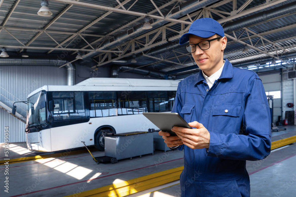 Poster Serviceman with digital tablet on the background of the bus in the garage	