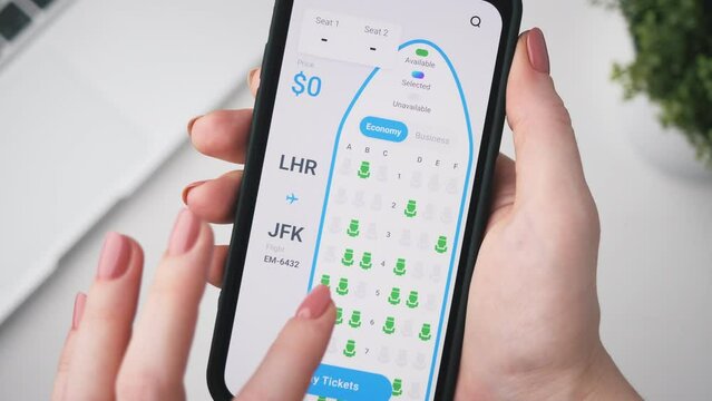Woman buys plane tickets online. Choosing seats in a plane using booking app for mobile phone.