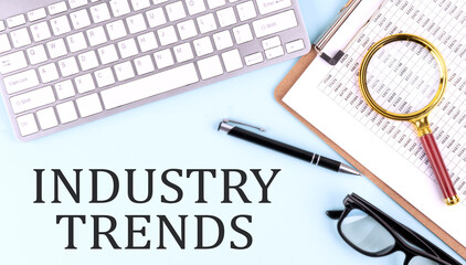 INDUSTRY TRENDS text on blue background with keyboard and clipboard, business concept