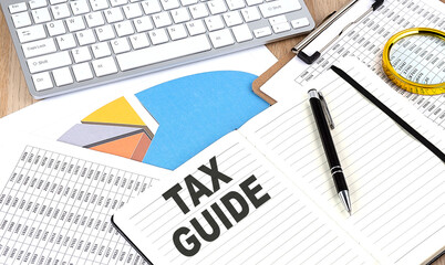 TAX GUIDE text on notebook with chart and keyboard