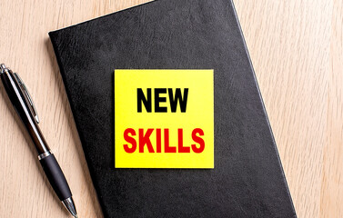 NEW SKILLS text on a sticky on black notebook with pen