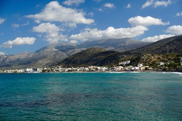 Aegean Sea in Crete. White clouds hang over the mountains. Azure water.	