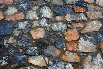Texture - a wall made of natural raw stone. Wet after the rain	