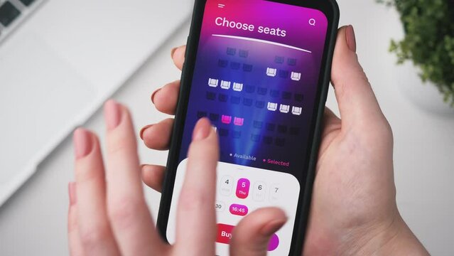 Woman buying cinema tickets online. Choosing seats in a cinema hall and buying ticketsusing app for mobile phone.
