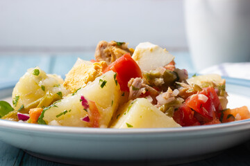 Close-up of potato salad with tomatoes, green beans, egg, tuna, onion and parsley. Mediterranean cuisine.