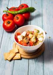 Mediterranean cuisine. Potato salad, tomato, egg, green beans, onion, parsley and tuna in a white bowl.