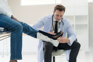 The doctor puts a splint on a patient with a leg. - obrazy, fototapety, plakaty
