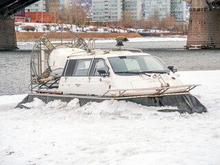 Hovercraft is standing on a snow-covered river bank