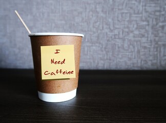 Coffee cup with handwritten sticky note I NEED CAFFEINE on copy space background, concept of...