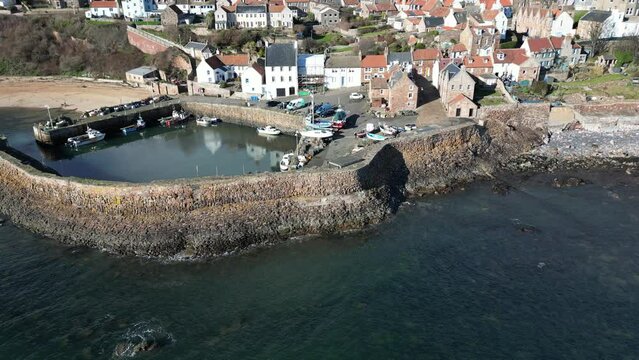 Crail, a historic fishing village on the east coast of Scotland in the East Neuk of Fife. Low level aerial footage of the pretty little harbour. Lovely reflections of whitewashed houses in the ripplin