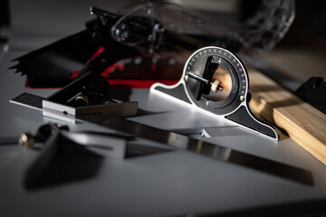 Next to a wooden board on a table saw, a carpenter's protractor is positioned on flat surface.
