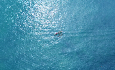 Aerial view of a fishing boat with fishermen in the blue ocean. Beautiful sea wallpaper for tourism and advertising. Asian landscape, drone photo