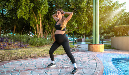 Full length of pregnant woman in sportswear exercising in the park.