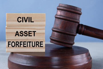The words CIVIL ASSET FORFEITURE on wooden cubes against the background of the judge's gavel and stand.