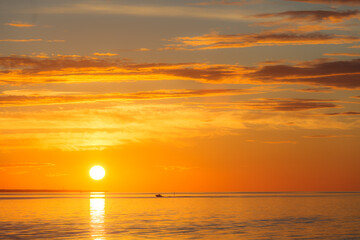 Sunset over sea, red colors, long clouds
