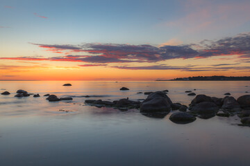 Fototapeta na wymiar Red colored sky over a rocky seashore. Sunset landscape.