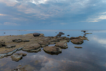 Beautiful sea shore view with with moss-covered rocks. Algae growing on seaside rocks. Blue hour time