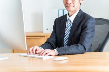 パソコン作業をするシニア日本人男性